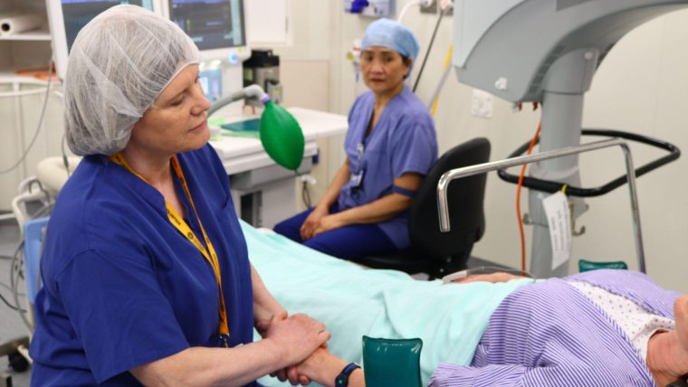 Friends of Moorfields volunteer holding a patient's hand in the hospital.