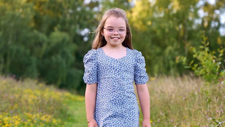Darcy Griggs wearing a blue dress and standing in a field.