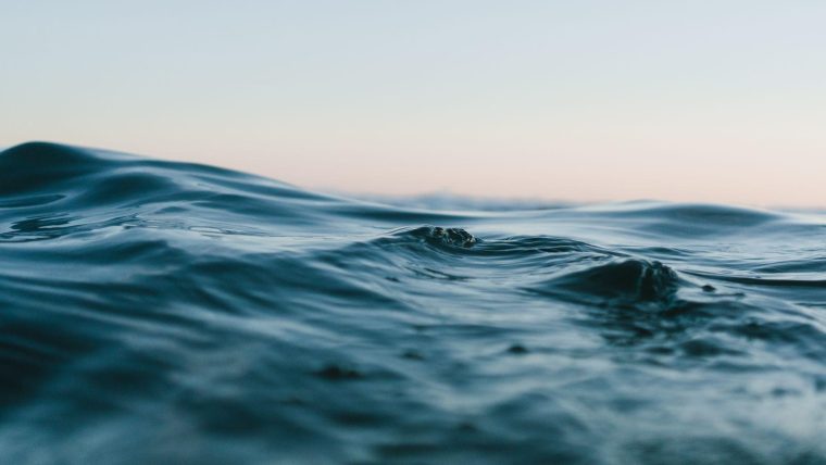 the surface of a body of moving water, set against a sky at sunset