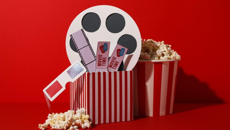 Paper cup with popcorn and box with movie supplies