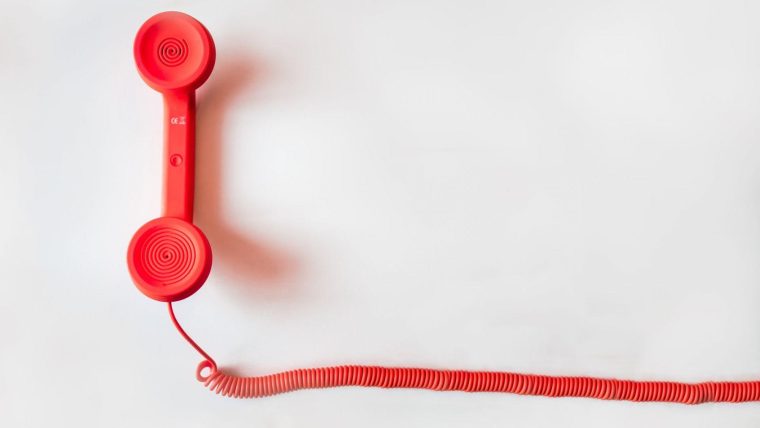 a red telephone handset with a long coiled chord